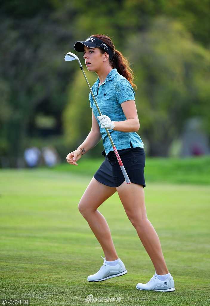 冯珊珊与球童在赛场上专注交流，两人并肩查看码数本，商讨下一杆的策略。