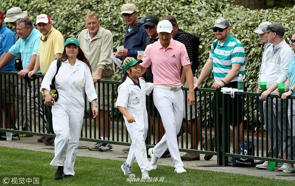 温情挥杆奥古斯塔:李昊桐与家人的大师赛温馨时刻 李昊桐在练习果岭上全神贯注地推杆,目光如炬,背景是奥古斯塔经典的会所与观众看台