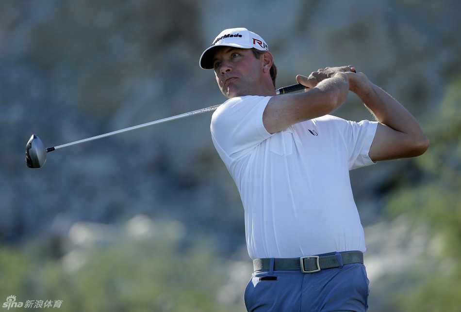 卢卡斯-格罗乌尔在发球台凝神准备，背景是开阔的球道与远方起伏的果岭