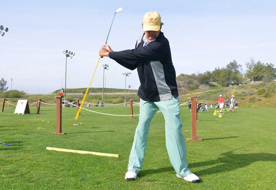 一位学员在沙坑中全力挥杆，沙粒如金色浪花般飞扬，阳光穿透沙幕映照出他充满力量感的动态瞬间