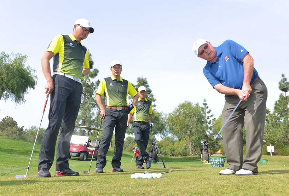 教练与学员围成一圈，低头共同观察地面上的球位，构成一幅充满研讨与学习氛围的生动画面