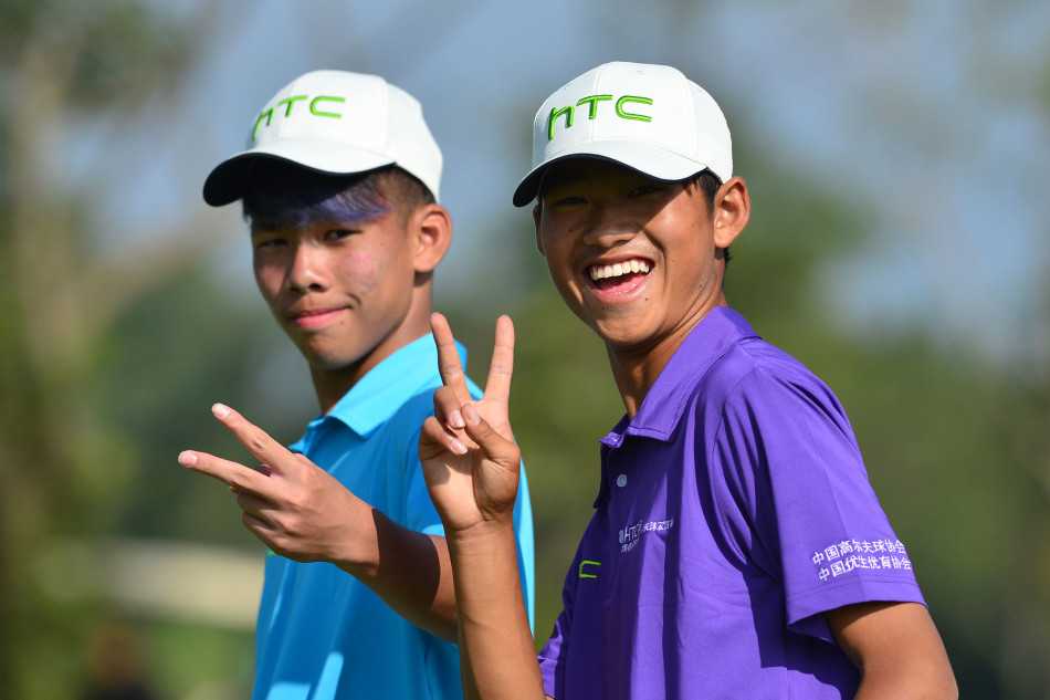 果岭边的博弈与情谊青少年高尔夫赛事中的专注时刻与团队精神 两位队员站在果岭旁,聚精会神地研究推杆的路线,为接下来的关键一击做足准备。