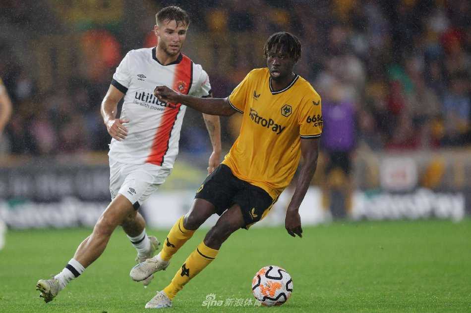 莫利纽克斯球场全景：看台被金黄色的灯光点亮，宛如一座中世纪城堡，球迷的身影在渐深的夜色中化作跃动的剪影，期待着新赛季的烽火重燃。