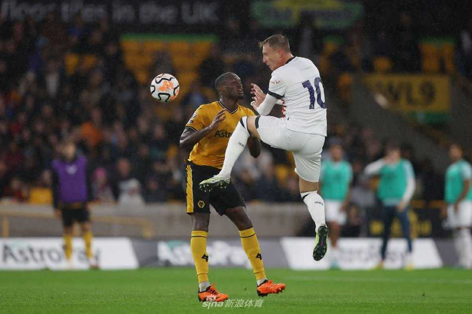 狼队前锋带球突进：橙色球衣的进攻球员如一道闪电撕开黄昏的绿茵，防守队员紧追不舍，双方肌肉紧绷的对抗瞬间凝固，充满了力量与速度的张力。