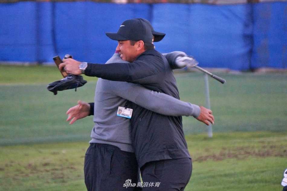 老虎伍兹与澳大利亚名将简森·戴伊在练习果岭旁亲切拥抱交谈，两位不同时代的顶尖球员之间充满尊重与友谊。