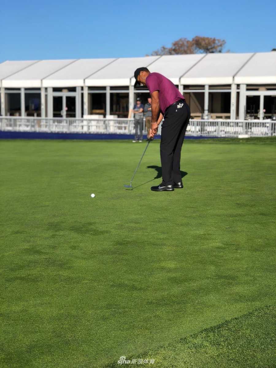 老虎伍兹在练习场凝神观察同组球员简森·戴伊的开球动作，专注的神情体现了他对比赛和对手的认真态度。