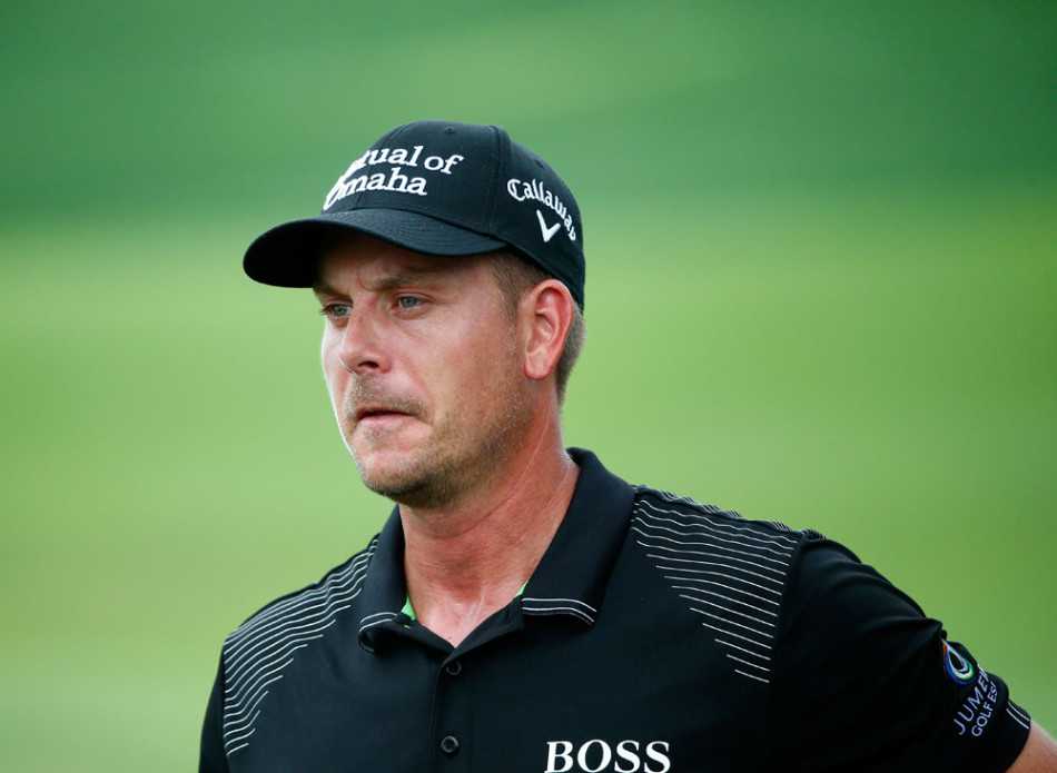 罗里·麦克罗伊站在球道上，双手扶杆，眉头微蹙地望着远方，脸上露出些许纳闷与困惑的表情，似乎在判断突如其来的风雨或评估棘手的球位带来的挑战。