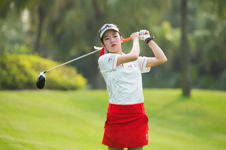 少年沉稳站立于发球台，凝望远方球道，蓄势待发的专注姿态