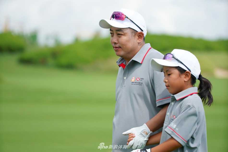 刘国梁俯身细心指导女儿握杆姿势，眼神专注充满慈爱