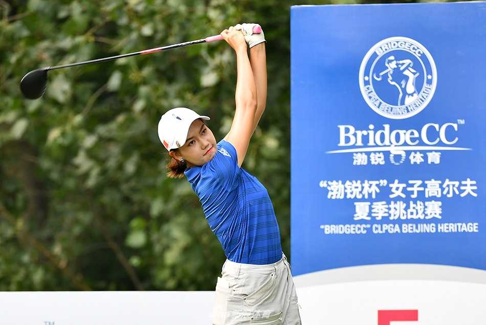 隋响与王馨迎在练习果岭边亲切交流，隋响手指前方似乎在探讨球路，展现了队友间的默契与互助。