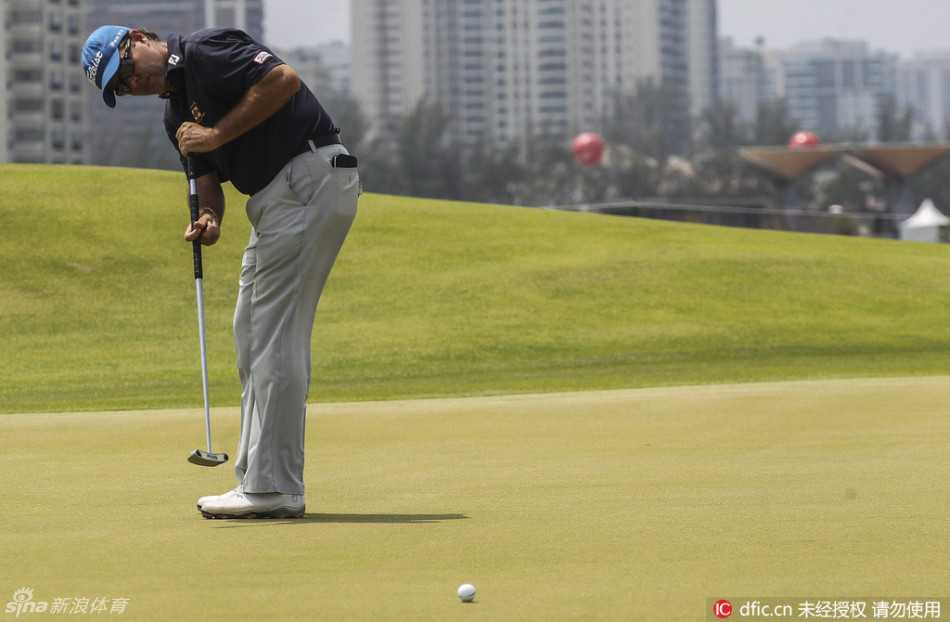 夕阳余晖映照下的奥林匹克高尔夫球场全景，水障碍波光粼粼，整个球场宁静而美丽，静待八月奥运大战。