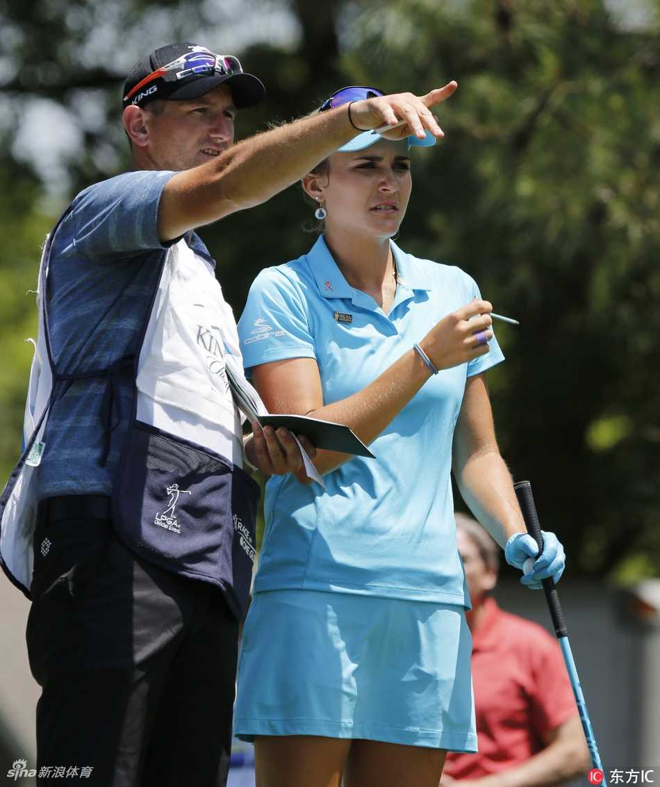 莱克西·汤普森与她的球童在赛道上并肩而行，认真讨论下一杆的策略，默契的配合是胜利的重要基石。