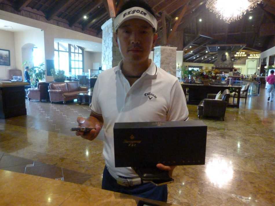 活动现场，一位工作人员正微笑着向球手递上印有芙蓉王标识的‘百鸟争鸣’礼盒