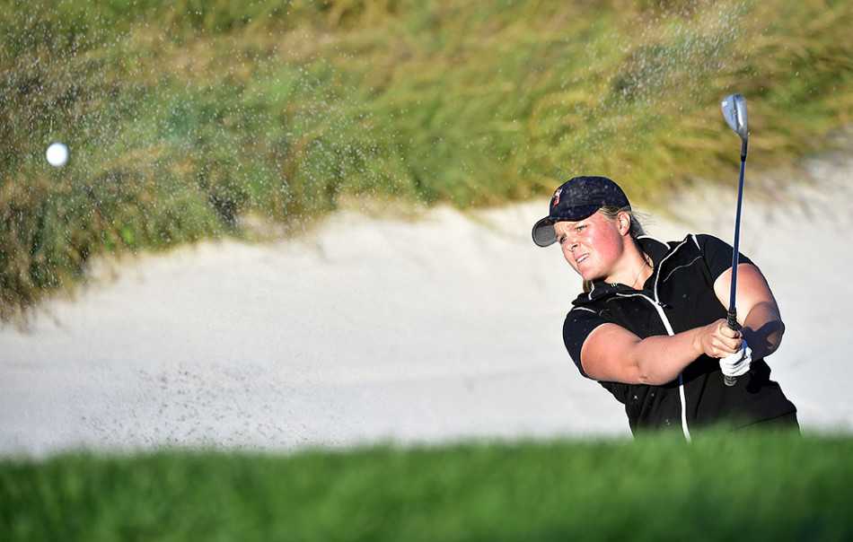 高球女将挥杆破沙，沙坑中炸起一片金色烟幕，小白球破雾而出