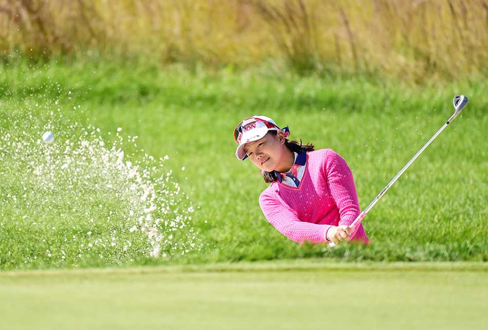 小白球静静卧在果岭环旁，远处是选手凝神思考的剪影，赛场氛围宁静而紧张