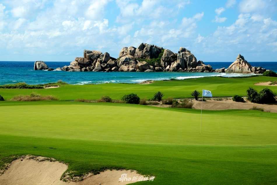 从空中俯瞰，翡翠般的球道在棕黄色沙丘与深蓝海水之间穿梭迂回，形成一幅色彩鲜明、充满动感线条的抽象画。