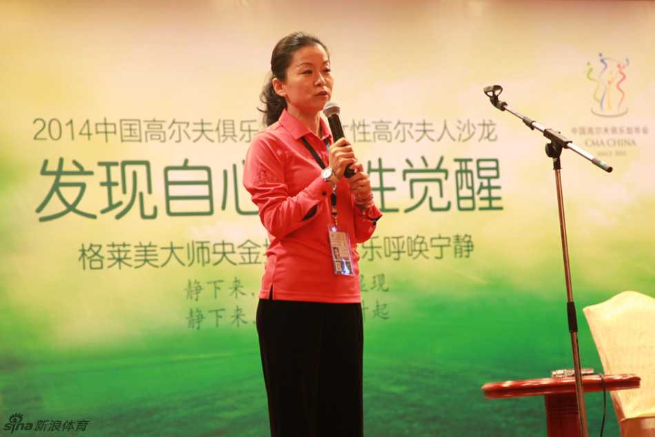 蒋雪梅女士手持话筒正在致辞，她目光坚定而温柔，身后沙龙背景板上的花卉图案仿佛随着她的话语静静绽放