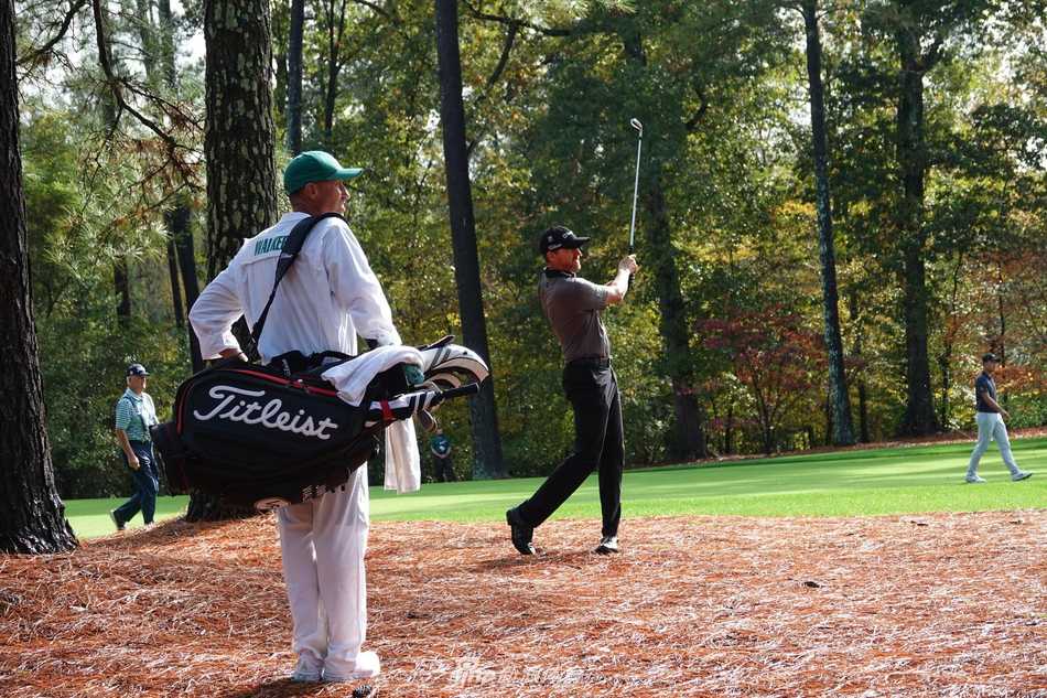 老虎伍兹全神贯注凝视沙坑中的高尔夫球，计算着下一杆的精妙弧线