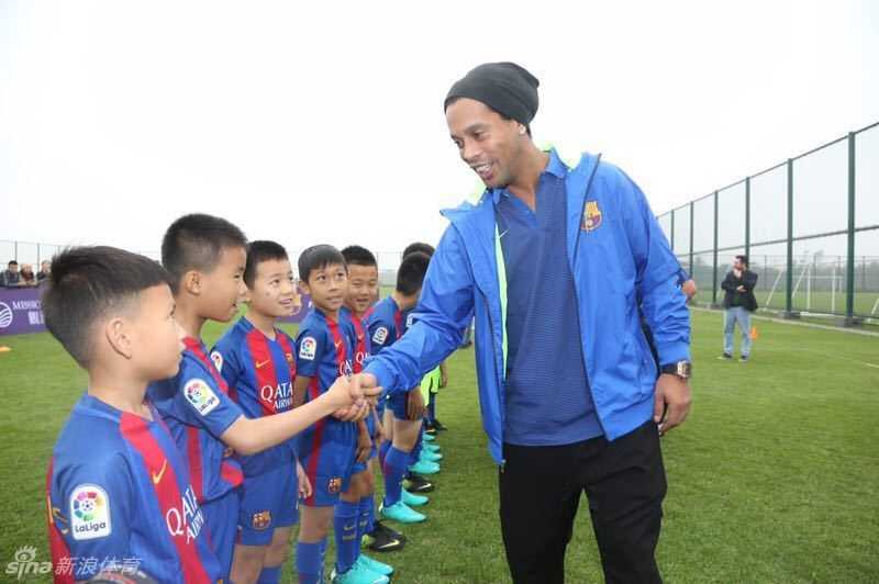 罗纳尔迪尼奥亲切地搂着小球员的肩膀合影，脸上洋溢着如阳光般温暖的笑容，瞬间拉近了与孩子的距离。
