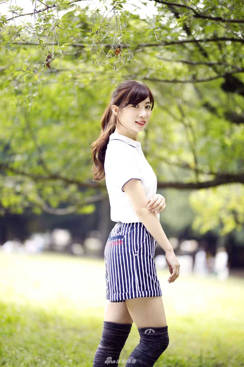 身着修身Polo衫与短裙的女士在绿地中侧身而立，展现出高尔夫着装的经典与简约之美。