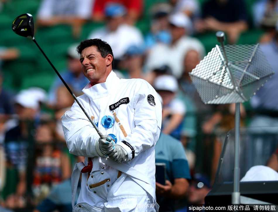 麦克罗伊与加西亚身着臃肿的白色宇航服，并肩站在高尔夫球场上，仿佛两位刚刚着陆的外星访客，背景是葱郁的树木与草地，形成强烈反差。