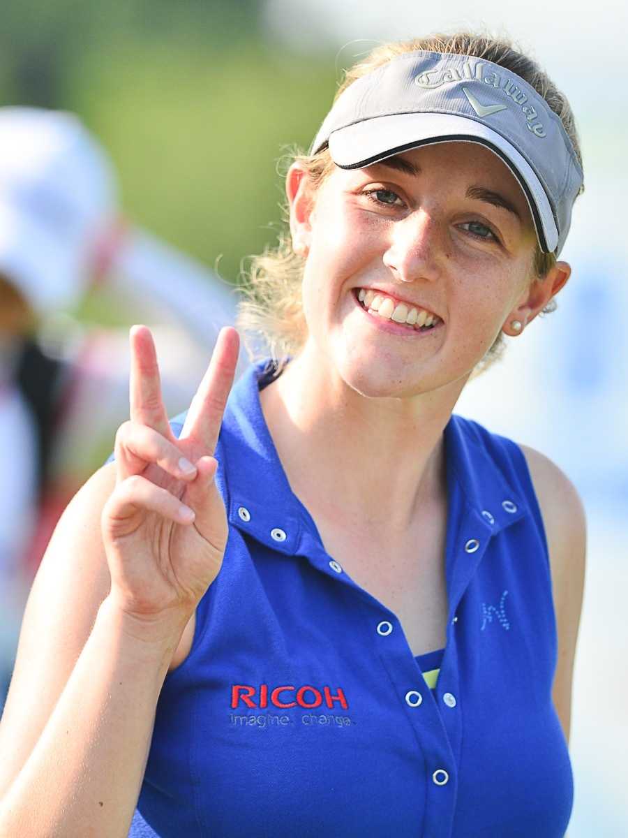 比利时选手克洛伊·勒奎妮站在发球台上极目远眺，评估球道策略，微风拂动她的发丝。