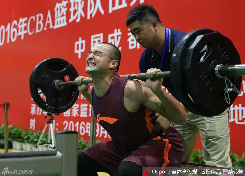 吉喆在进行深蹲测试，他紧咬牙关咬住自己的衣领，双眼圆睁，表情既搞笑又充满力量感。