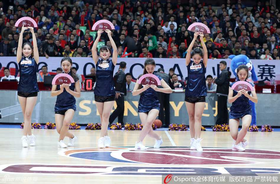 CBA赛场上的美丽风景线 篮球宝贝热舞瞬间点燃冬日激情 在灯光聚焦的赛场中央,一位篮球宝贝高抬腿展示修长美腿,背景是巨大的CBA联赛标志和热情的观众。
