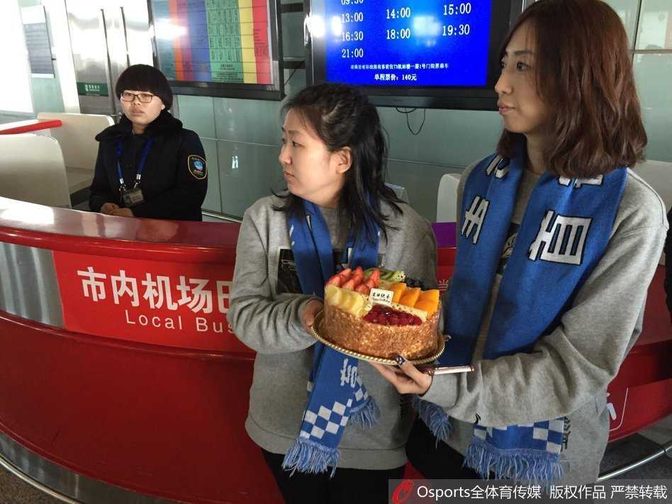 机场大厅一角，一位忠实的男球迷双手稳稳托举着一个特制的生日蛋糕盒，耐心等待马布里经过。蛋糕盒上装饰着首钢队的元素，这是球迷们为偶像精心准备的生日惊喜。