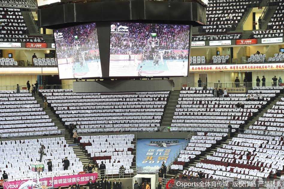 球迷们手持白色助威衫陆续入场，现场气氛热烈，但部分座位因助威衫被收走而出现了颜色不一的缺口。