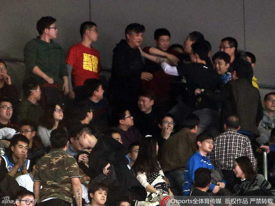 人潮拥挤的看台通道内，几名戴着蓝色帽子的安保人员奋力组成人墙，用身体隔开情绪亢奋的球迷，球迷们则踮起脚尖、伸长脖子，试图从人墙缝隙中挤向前方。