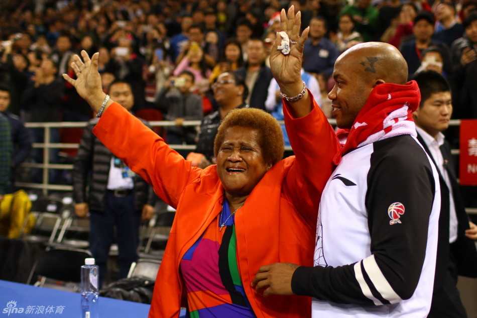 马布里搀扶着腿脚不便的母亲，小心翼翼地在更衣室通道中前行，他的眼神始终关注着母亲的脚步，画面温馨而感人。