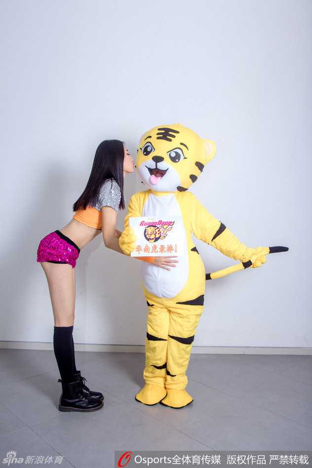 两位篮球宝贝紧紧抱着那只顽皮的华南虎吉祥物，虎头在两人中间被挤得有些变形，但依然努力保持着标志性的咧嘴笑，这张搞怪合影将赛场下的轻松友爱定格成了永恒。