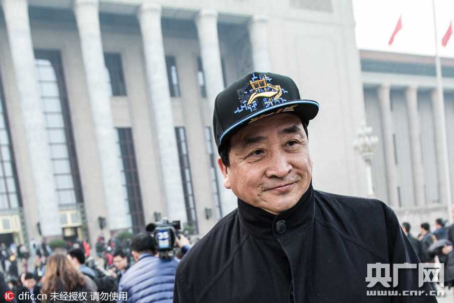 在热烈的分组讨论间隙，姜昆手持会议材料与身旁委员热络交流，身后的会标与眼前专注的神情构成一幅生动的议政图景。