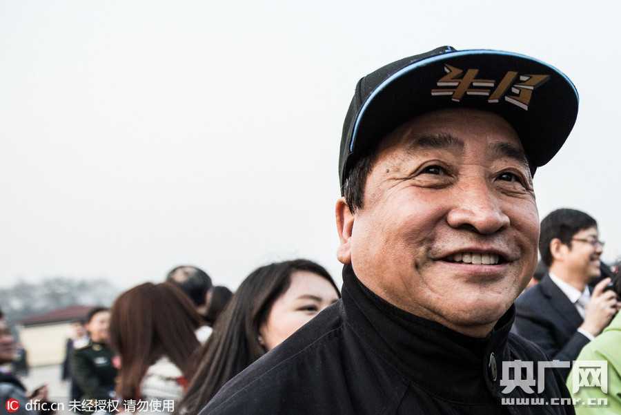 面对簇拥的话筒与录音笔，姜昆身体微微前倾专注倾听记者提问，神情平和亲切，那顶醒目的北京冠军帽在镜头中成为最独特的背景。