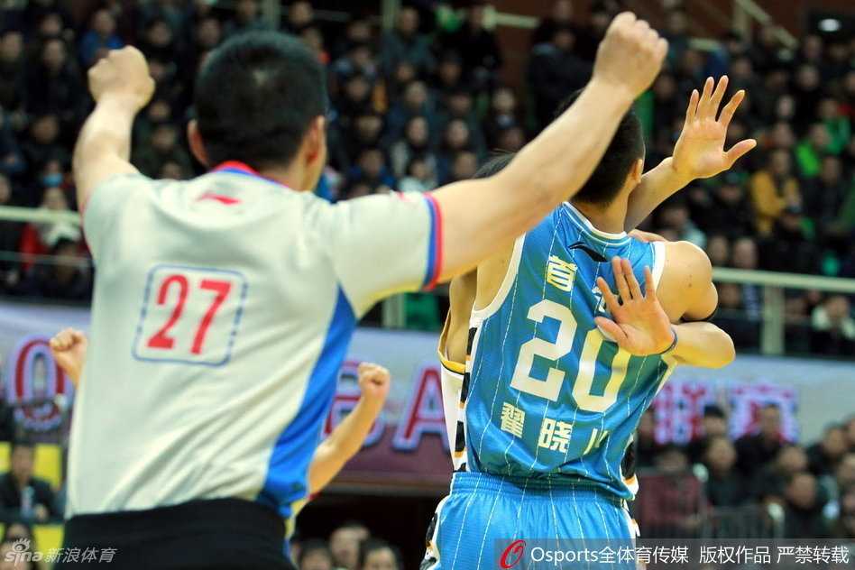 北京队球员情绪激动地将翟晓川护在身后，对着裁判不停比划着手势，试图解释刚才的判罚，而翟晓川则一脸委屈与不甘，紧握双拳。