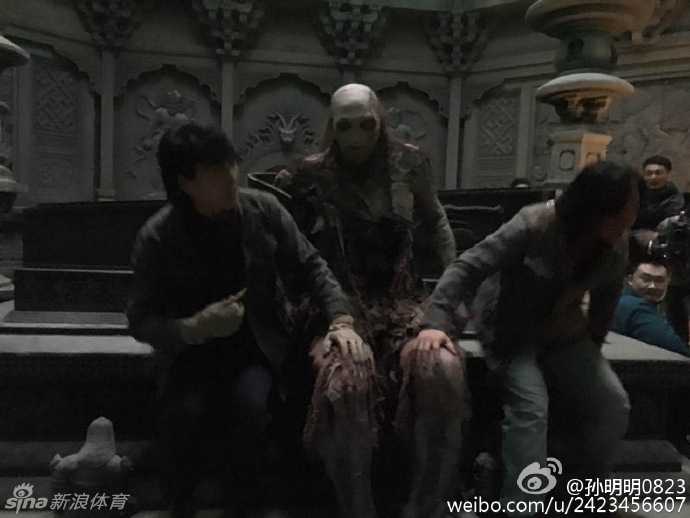 片场休息时的孙明明，还没来得及卸下身上厚重的‘红犼’戏服。在春日暖阳的照射下，这具在古墓中本应不见天日的恐怖丧尸，却惬意地坐在小板凳上晒太阳，巨大的身躯与脚下小小的板凳形成鲜明对比，形成了一种极具冲击力的魔幻现实感。
