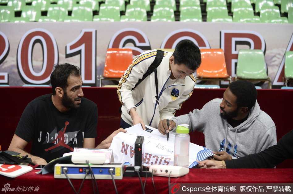 球迷围拢中，外援哈里斯低着头在球衣上勾勒出自己的名字，嘴角却藏着一丝即将恶作剧般的狡黠笑意，仿佛心里正盘算着待会儿如何捉弄队友