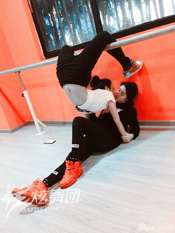 一位舞者轻松完成一字马‘壁咚’，眼神中透露出自信与俏皮，仿佛在说‘这种小场面，根本不在话下’。