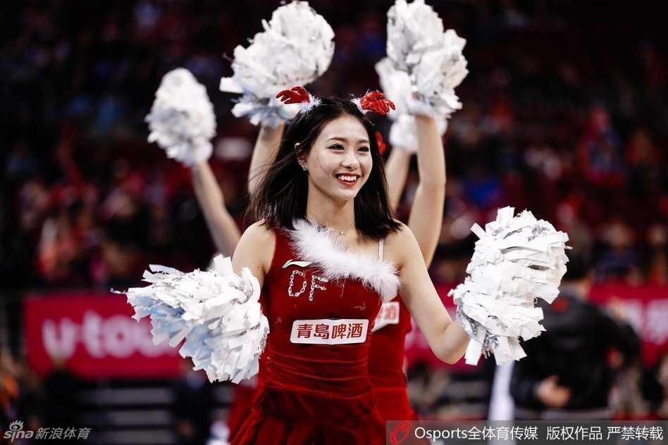一位队员的特写，她手持啦啦球花，背景是模糊的看台观众，红色的圣诞装和专注的神情完美诠释了球场上的节日氛围。