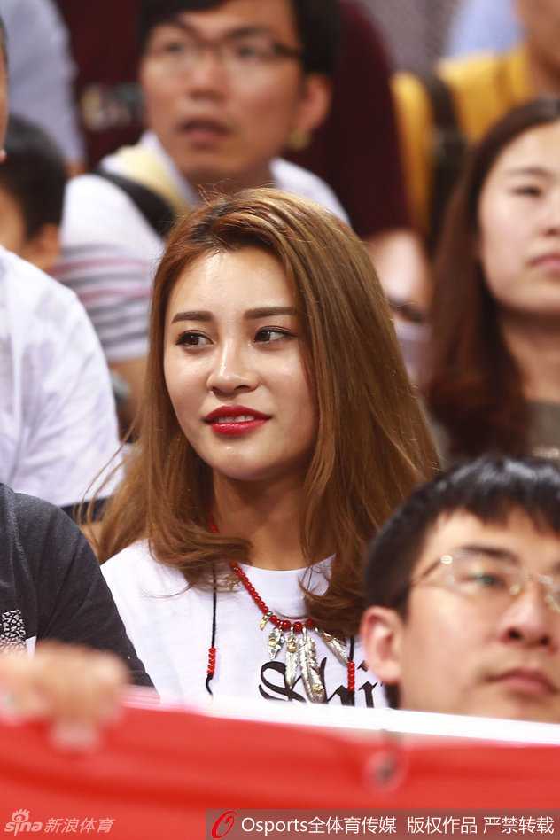 郭艾伦母亲与女友并肩而坐，母亲脸上挂着慈祥的微笑，女友略施粉黛，侧颜线条优美，聚精会神关注场内局势。