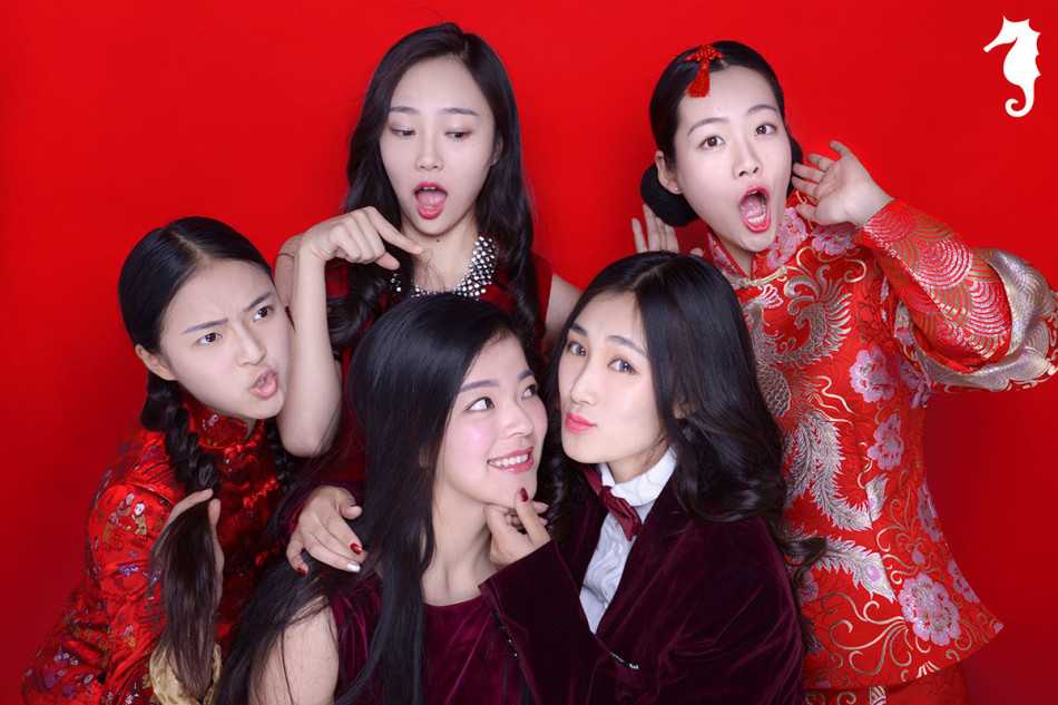 身穿火红连衣裙的小女孩歪着头露出甜笑，裙摆随着她轻快的步伐仿佛在跳动，像一团燃烧在冬日里的小太阳，暖化人心