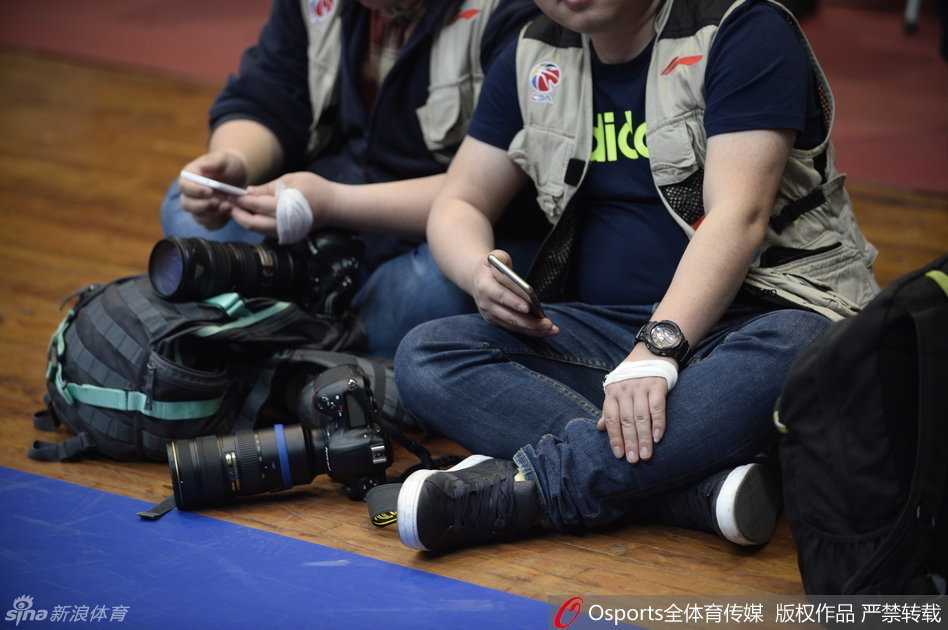 一名四川记者微笑着展示自己缠着绷带的手腕，身旁的同行们同样如此，他们围坐在一起交流，绷带无声地串联起一种微妙的默契，将赛场外的暗流涌动带入到紧张的赛前氛围中。