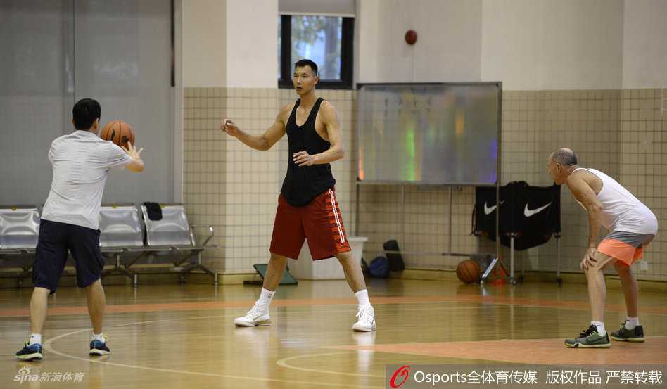 易建联在投篮练习中起跳至最高点，手臂完全伸展，手指尖拨出篮球，专注于每一个投篮动作的细节和稳定性。