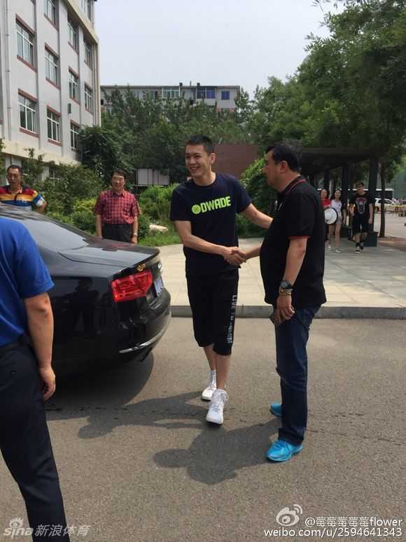 在一群学生和球迷的围绕下，杨鸣伸出右手，面带谦逊地与校领导进行亲切握手，场面融洽而热烈。