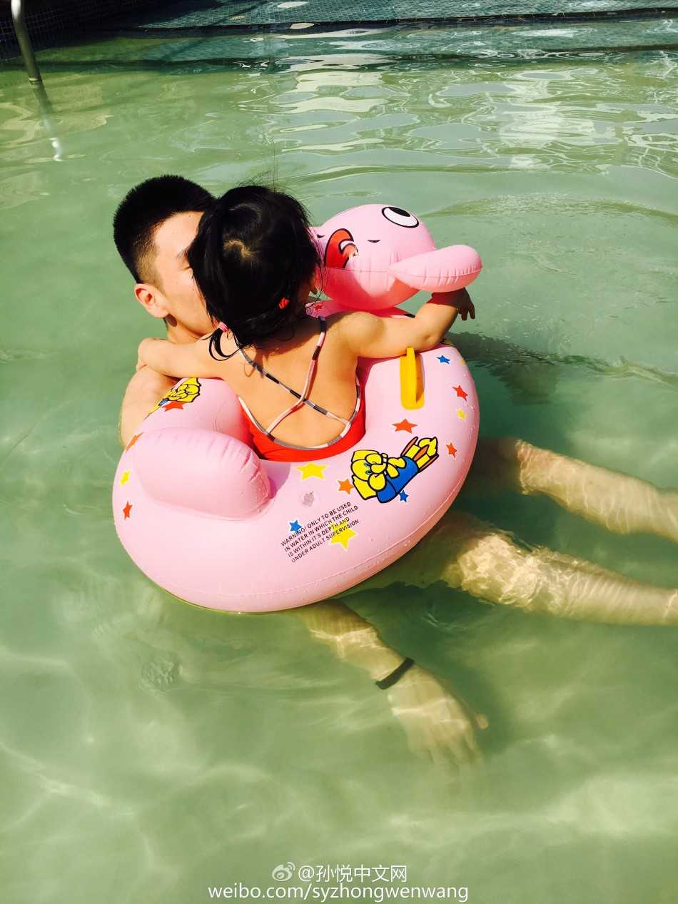 泳池里的超级英雄:孙悦与“小月亮”的温馨父女时光 小月亮独自坐在卡通游泳圈中漂浮在水面,孙悦在不远处微笑守护,画面宁静温馨