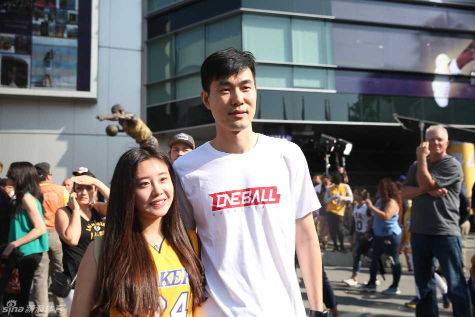 科比谢幕战六十光年,王仕鹏朱芳雨送别传奇,万人空巷只为一人 王仕鹏与女球迷合影时依然低头关注手机上的比赛信息,一旁的朱芳雨则面带微笑望向镜头,背景是人潮涌动的斯台普斯中心外场。