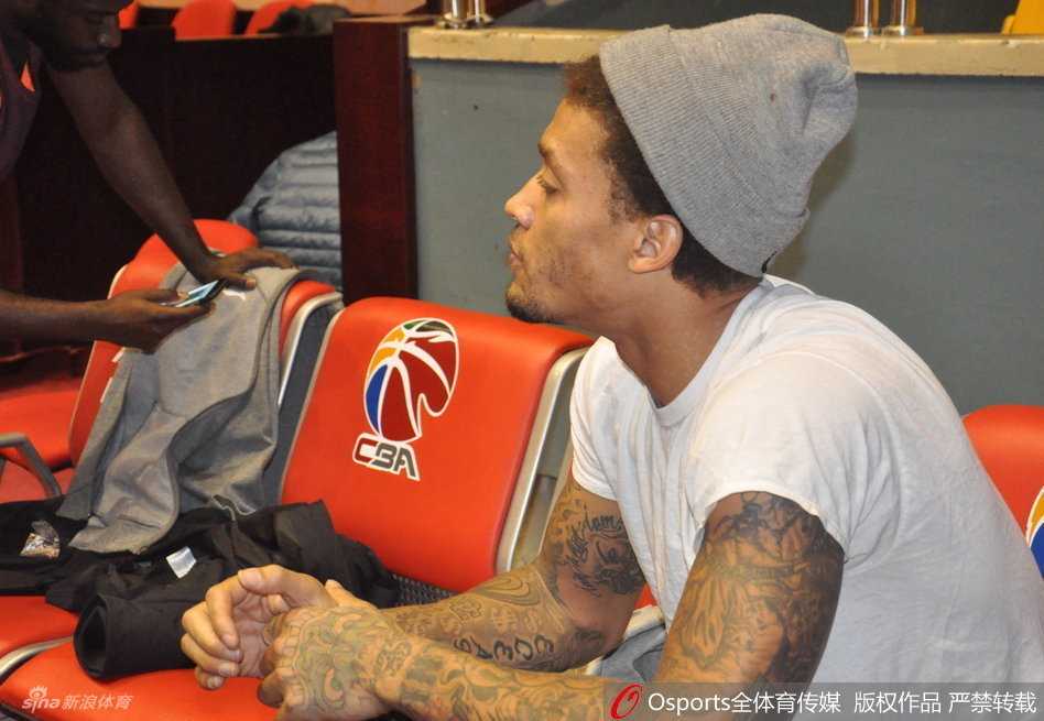 迈克尔·比斯利在训练中突然搞怪，用球衣蒙头扮鬼脸，一旁球鞋显眼，严肃的训练场瞬间充满欢乐气氛。