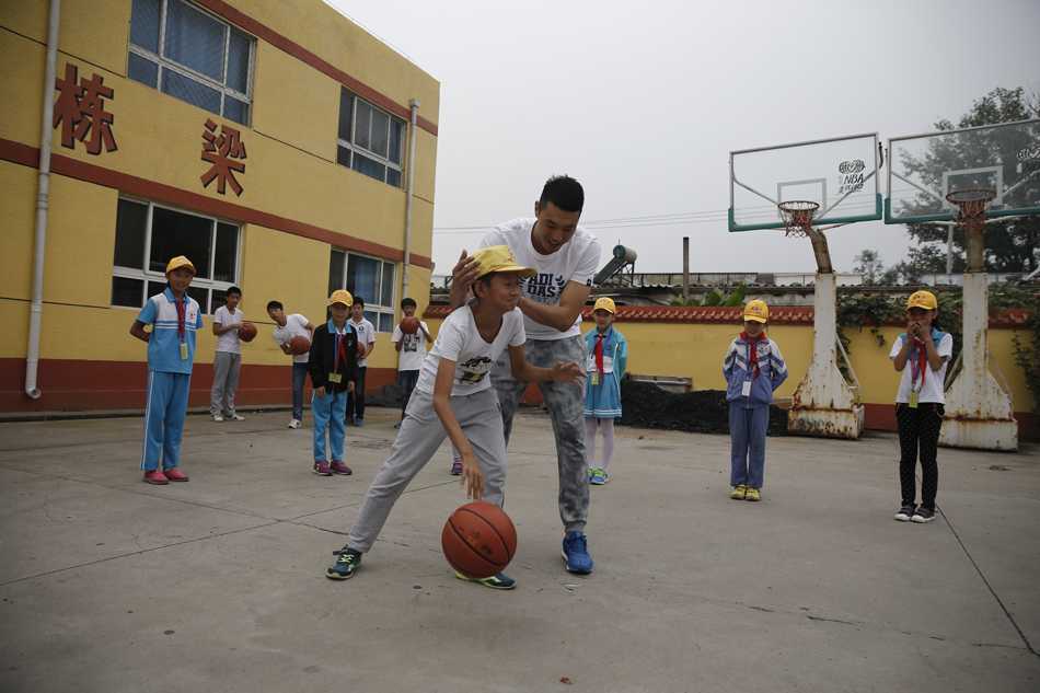 在尘土飞扬的简陋操场上，翟晓川亲自示范投篮动作，篮球在空中划出优美弧线，一群孩子仰头追随球的轨迹，眼中闪烁着对运动的热爱