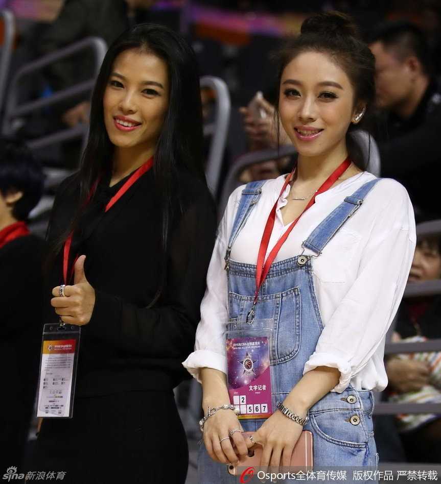 长发披肩的记者面对镜头露出略带羞涩却真诚的笑容，身后是模糊的赛场光影，衬托出她此刻的恬静与美好。